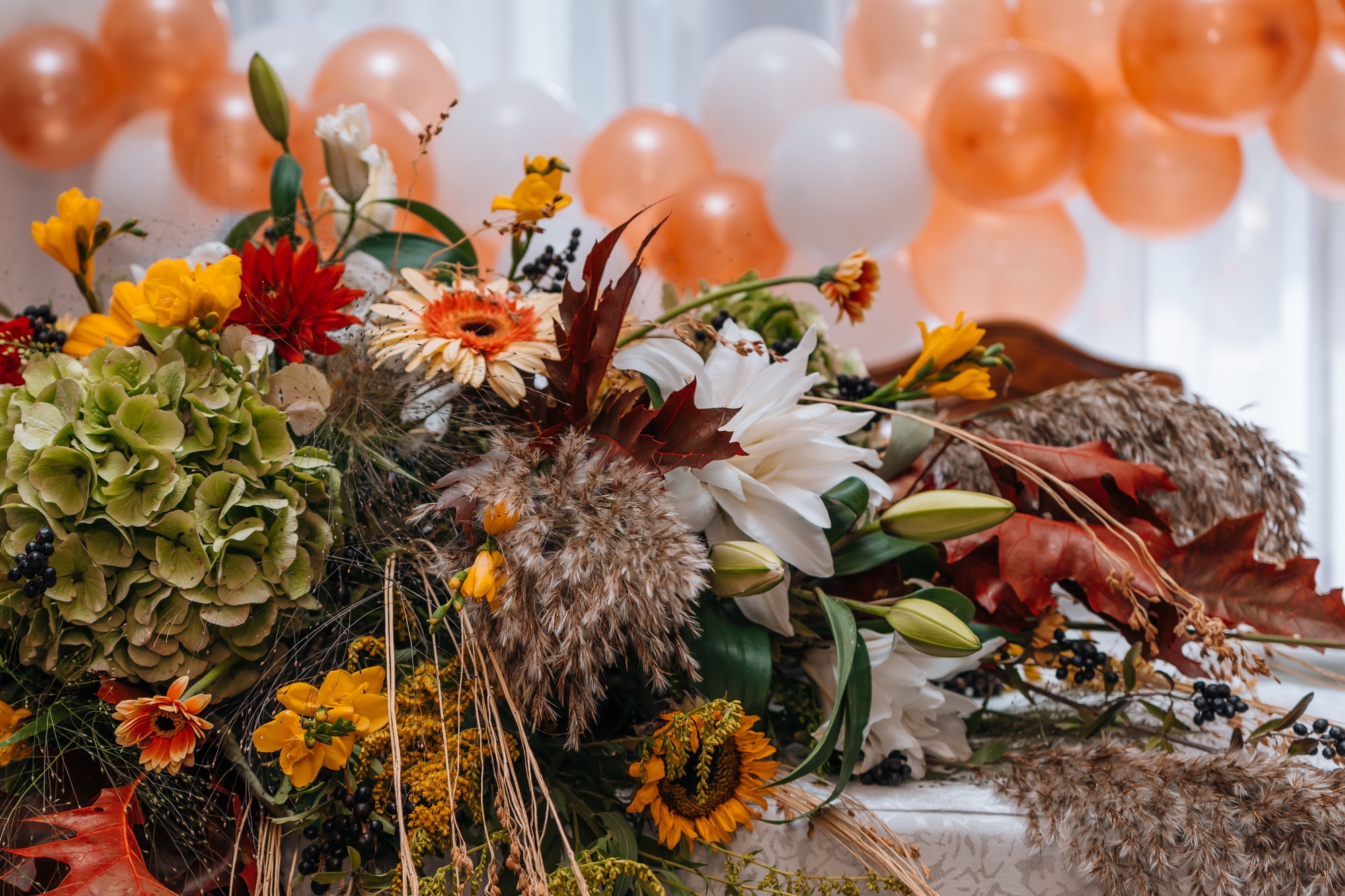 Event table decorated with a floral arrangement and balloons in the background
